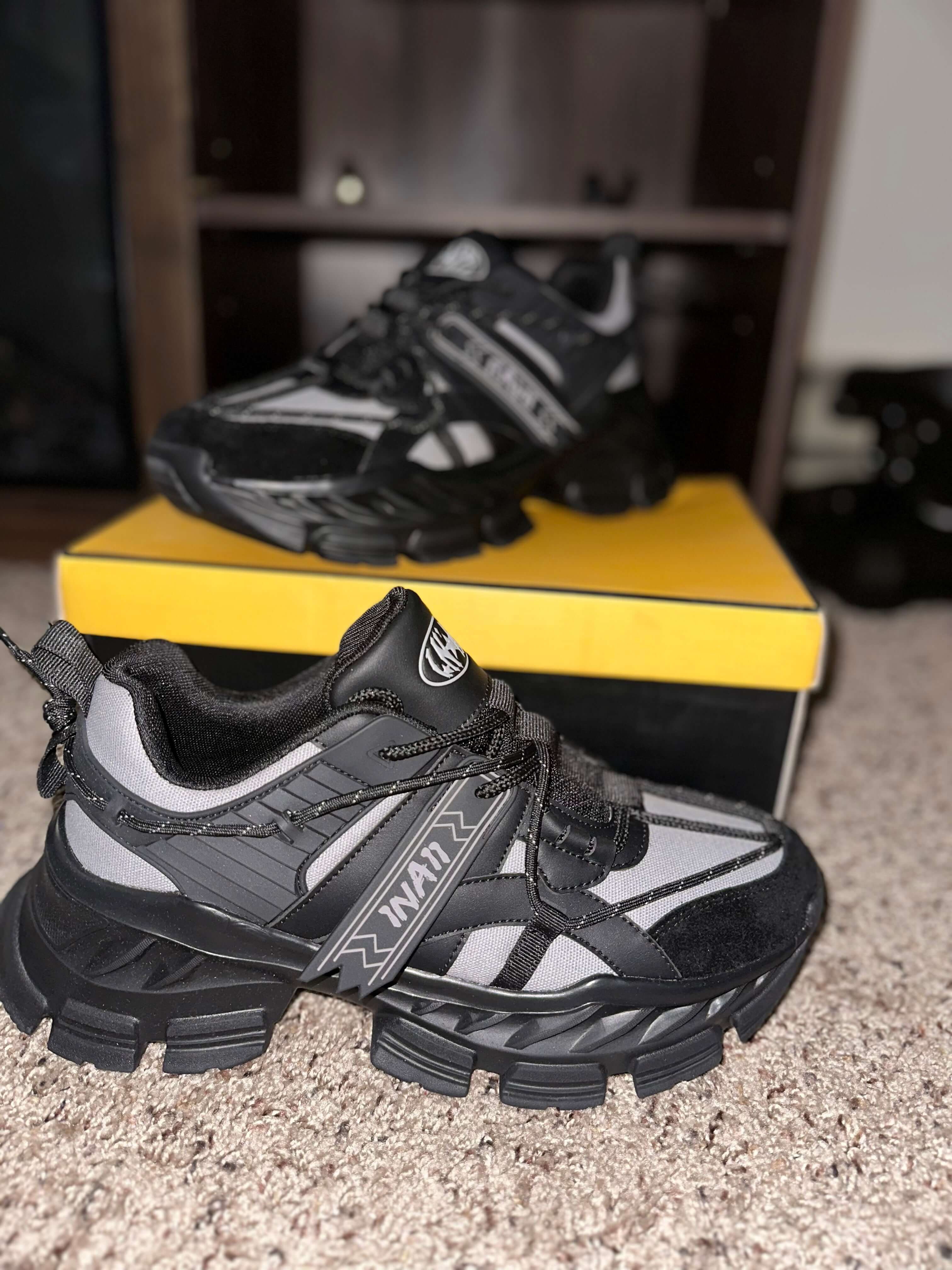 1 N' A11 Charcoal Glaze sneakers with black and grey design, showcased on a yellow box, perfect for stylish and comfortable everyday wear