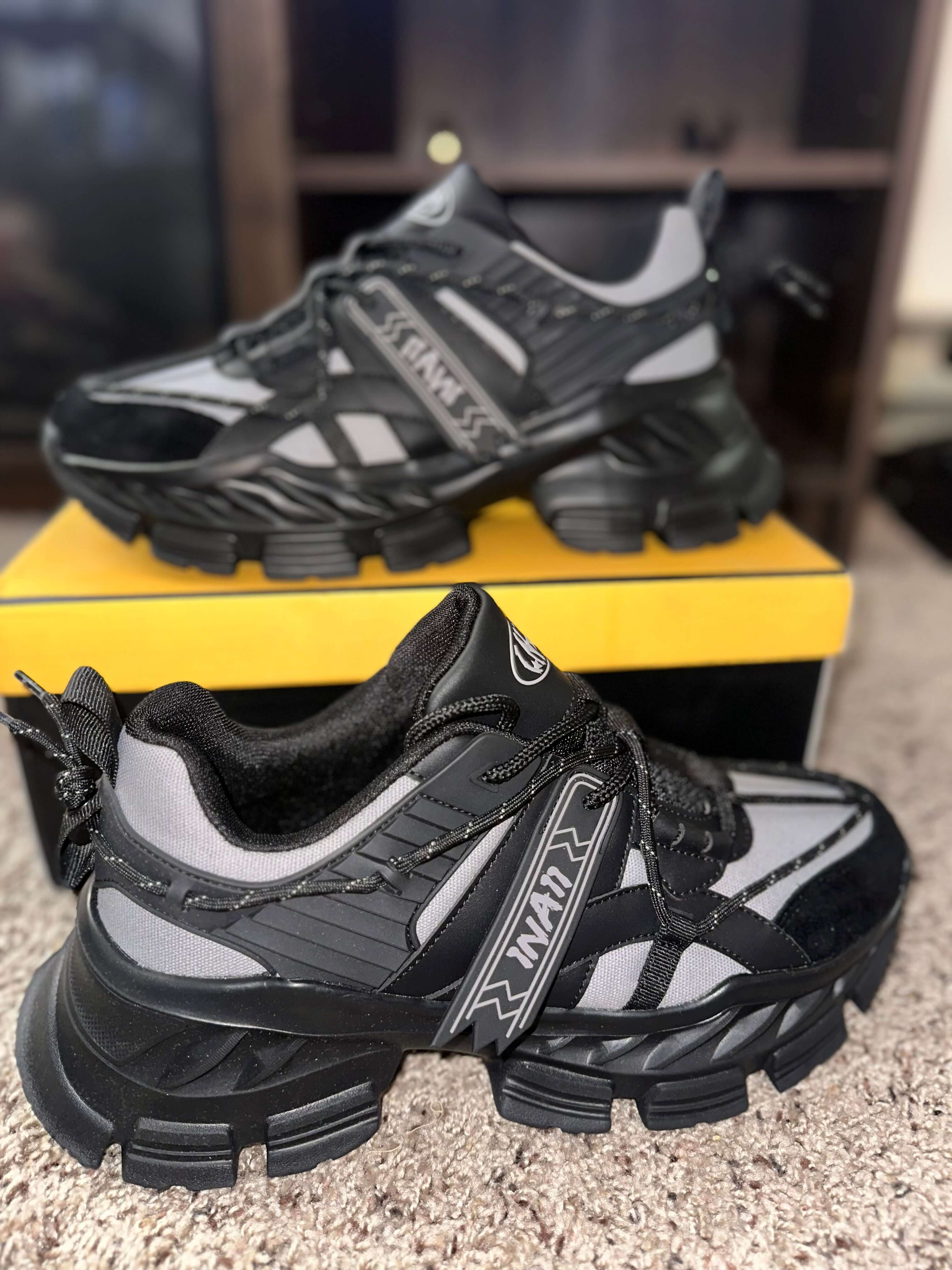 1 N’ A11 Charcoal Glaze sneakers with black and grey design on a yellow box, showcasing durable sole and intricate details.