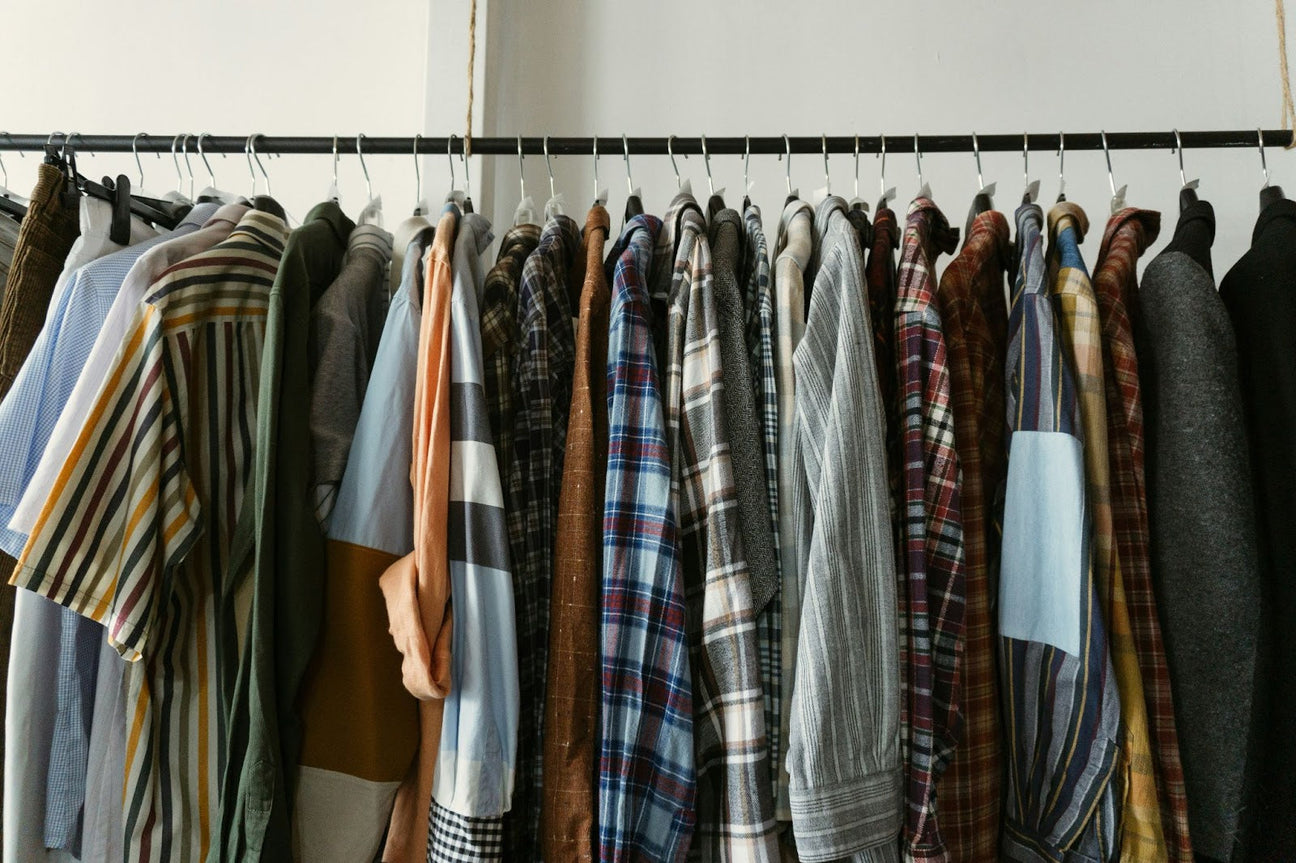 A collection of colorful plaid, striped, and solid shirts hanging neatly on a clothing rack, showcasing a versatile and stylish wardrobe.