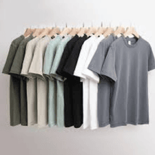 A collection of high-quality T-shirts in neutral colors like grey, white, black, and green hanging neatly on wooden hangers.