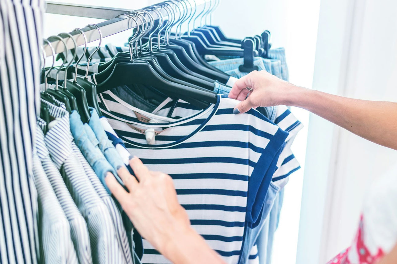 A person selecting stylish striped shirts, showcasing unique streetwear apparel options perfect for elevating a modern and versatile wardrobe.