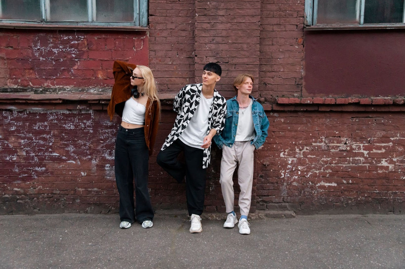 A group of friends showcasing streetwear outfits in casual yet stylish attire, standing confidently in front of a brick wall, perfect for layering streetwear.