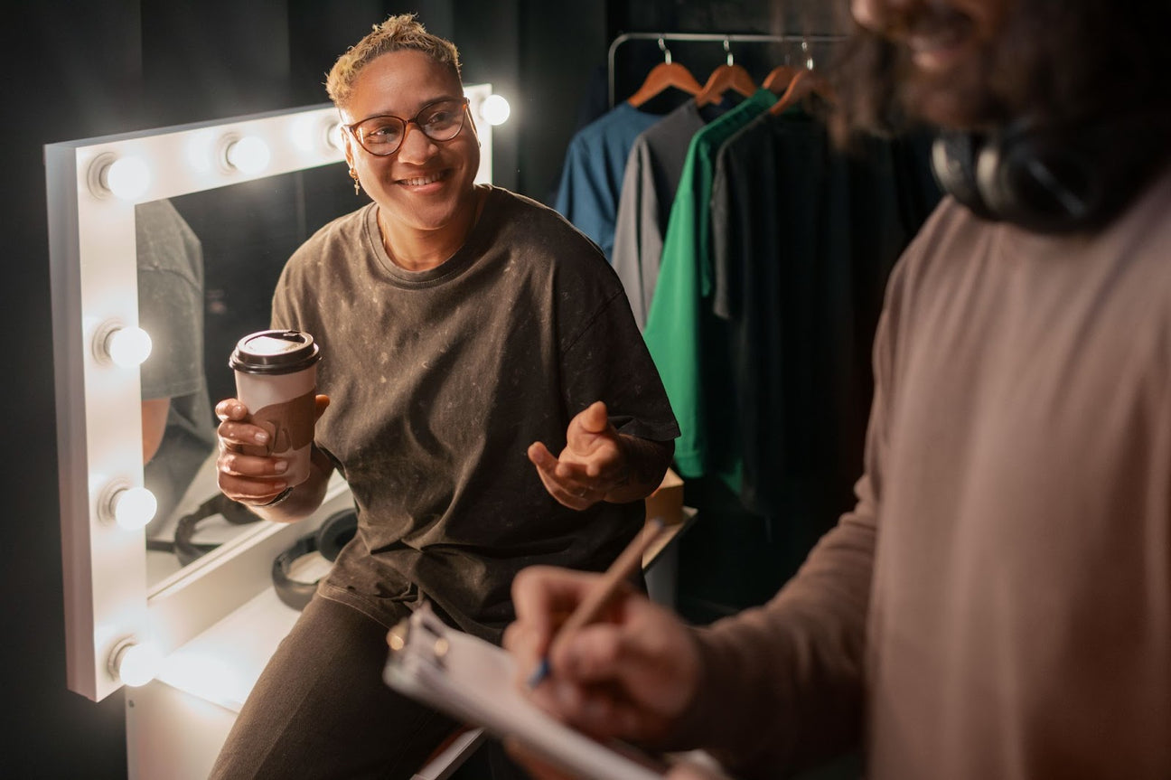  person enjoying a coffee while discussing designs in a cozy setting, surrounded by streetwear clothing, representing the creative and exclusive nature of 1na11apparel's streetwear brand